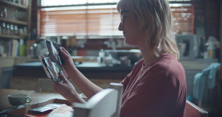A woman looks at photographs while sitting at a table indoors during the day