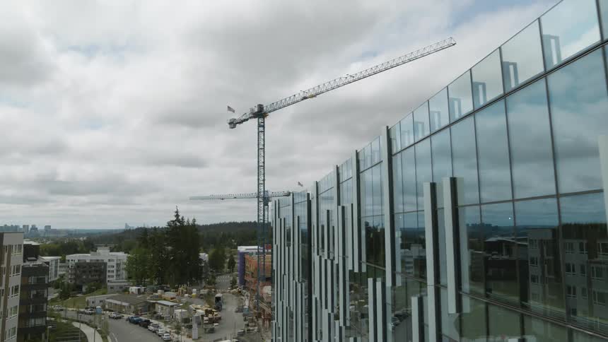 A tall crane towers above a gleaming new office building under construction in a business park