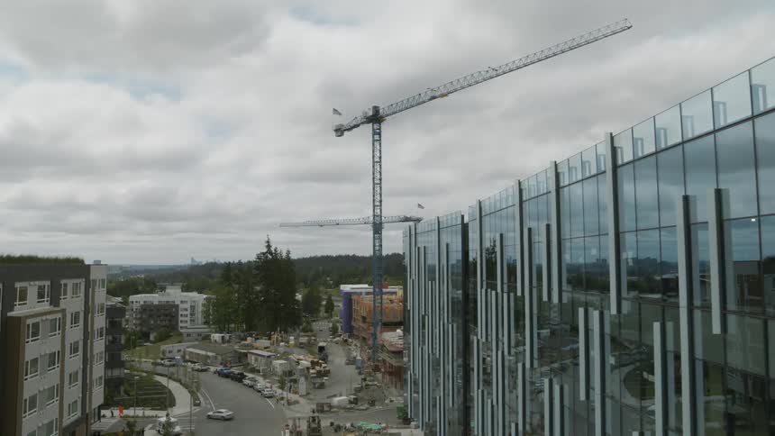 A construction crane stands above a nearly complete office building