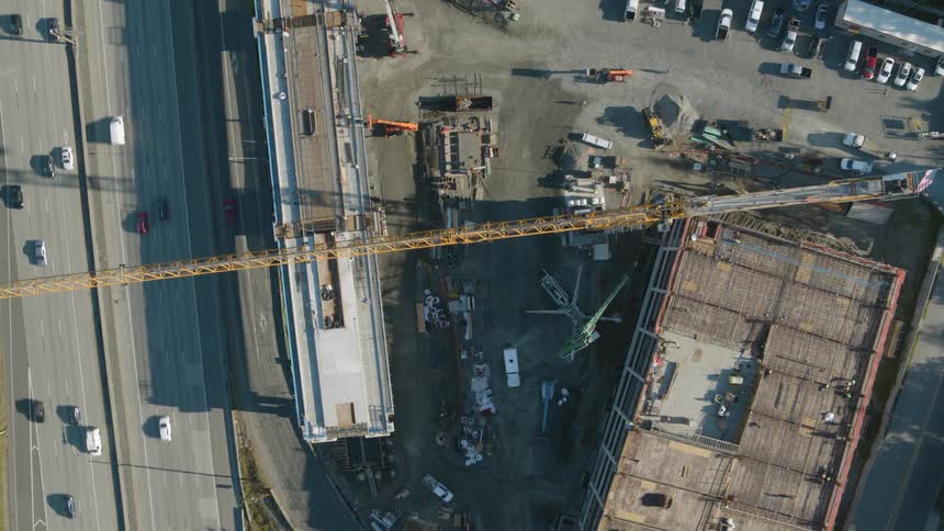 Top down view of an active construction site along a busy freeway