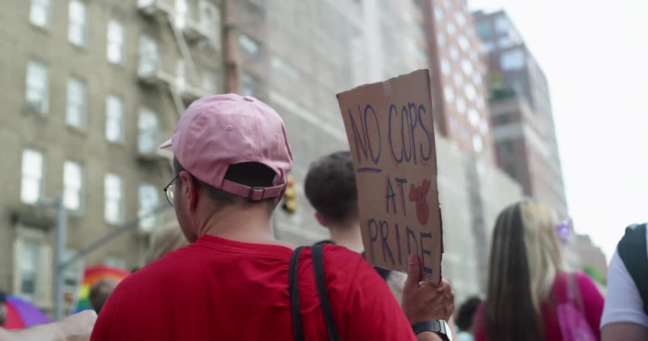 A group of people protesting and carrying signs outdoors during a large city pride event