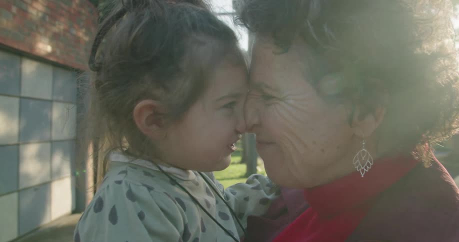 A woman and her granddaughter laugh while touching noses