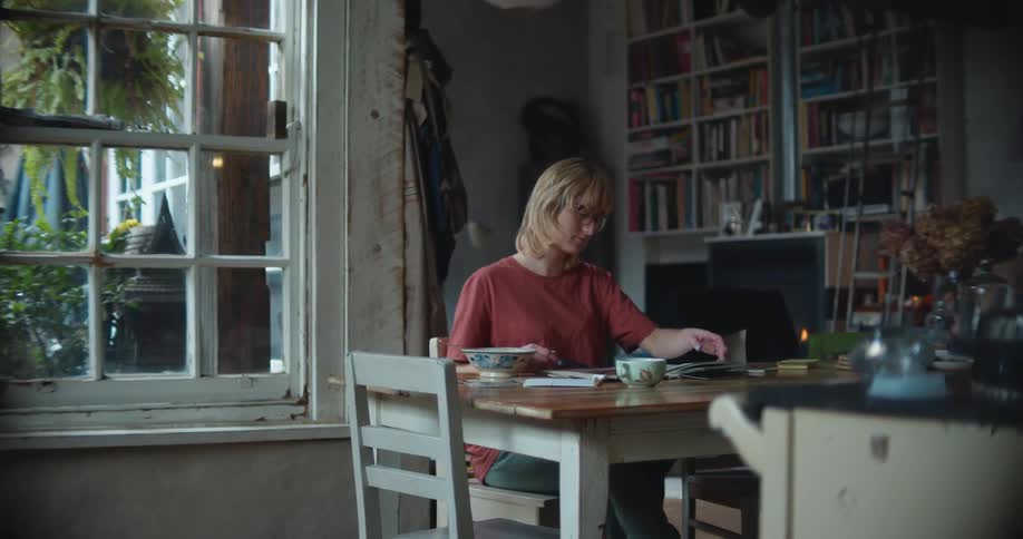 Woman sits at a table next to a fireplace and looks through a photo album