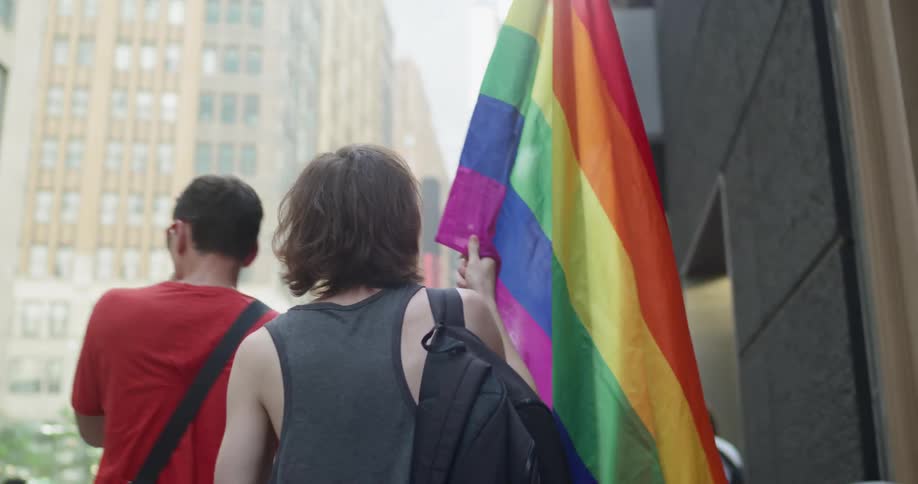 A man carries a large rainbow flag as he walks during a rally in support of gay rights