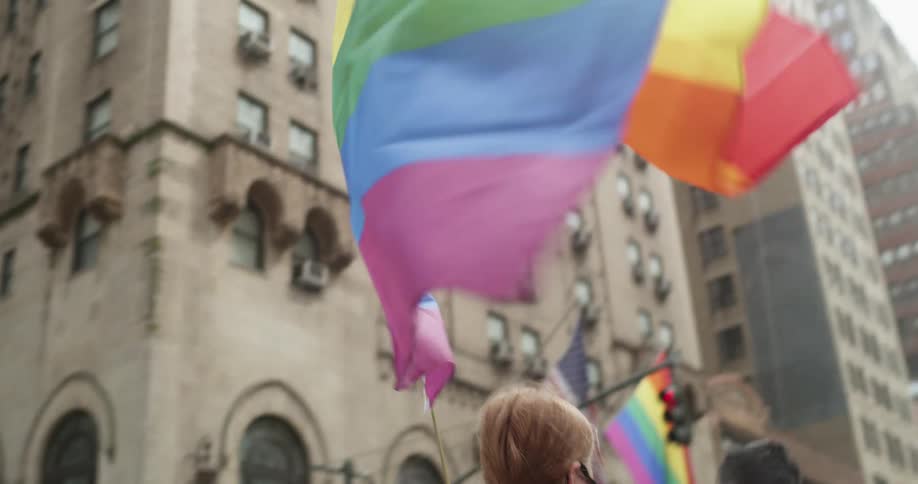 Women carry rainbow colored flags as they walk in a parade in the city