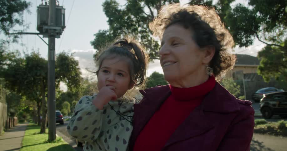 A grandmother is holding her granddaughter outdoors in spring