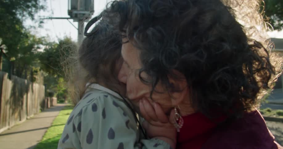 A little girl touches her grandmothers face as she smiles at her