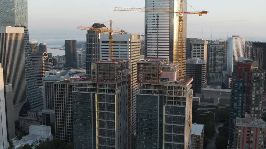 Pullback tilt up reveal of two new towers being built in the downtown area of a large city