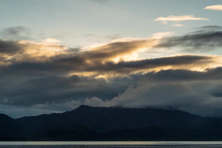 The sun rises and sets over a mountain and ocean