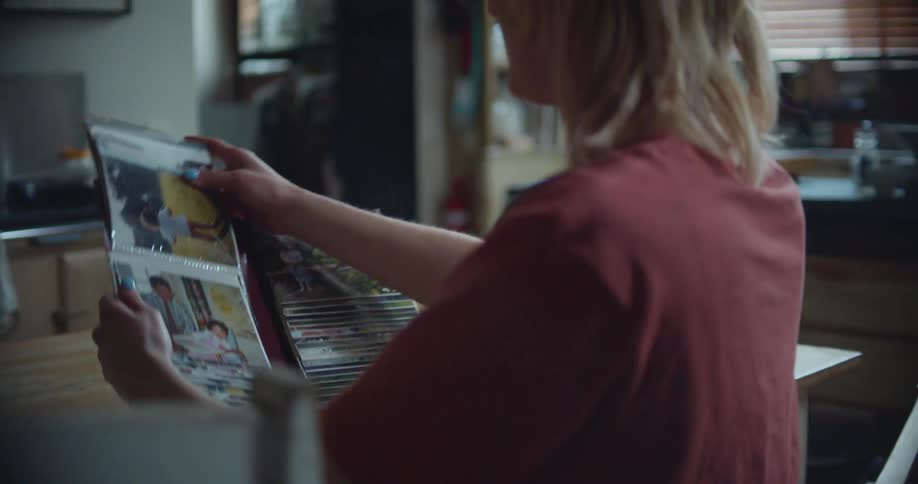 A woman in a room with glasses sitting at a desk looking at a picture album