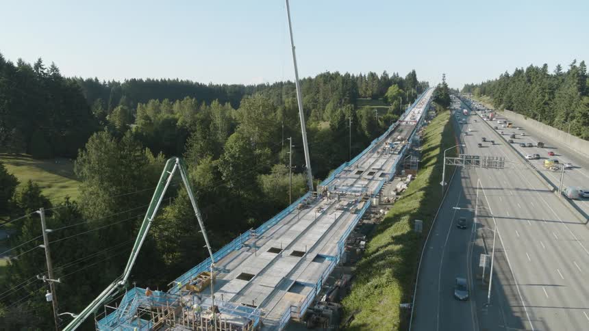 An above ground light rail transit deck is under construction next to a busy highway