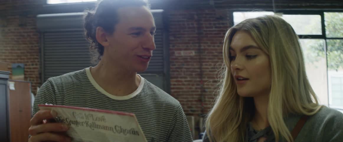 A man and woman review a vinyl album cover in a shop