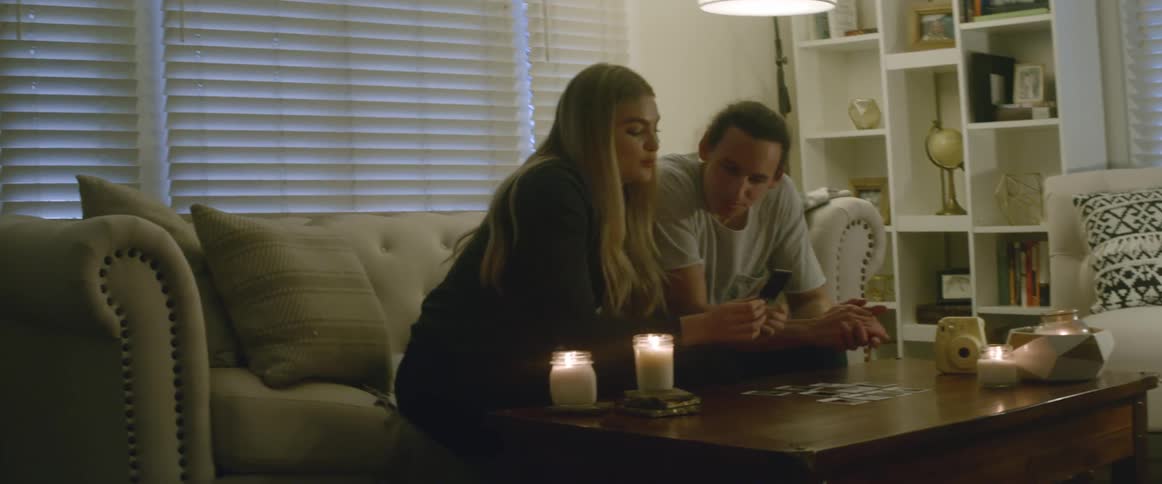 A man and woman sit in a living room looking at cards or photos