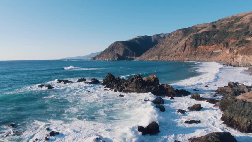 Waves crash against small rocks along the coast line
