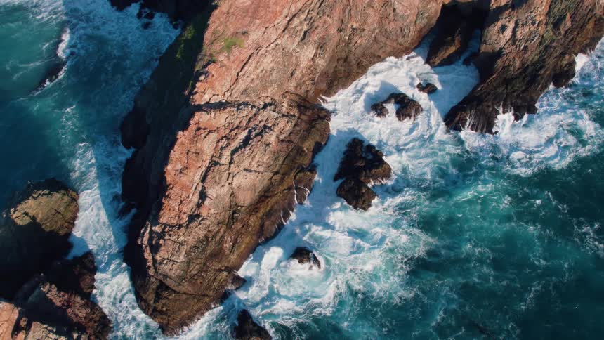 Aerial view of waves crashing into rocks