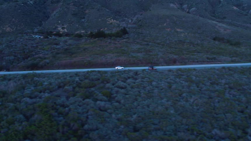 A car is driving on a road in a mountain area