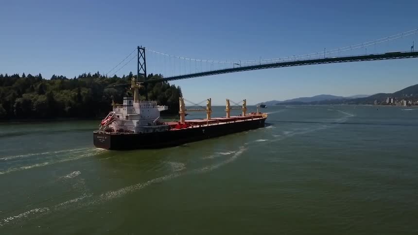 A large boat passing underneath a bridge on a clear day