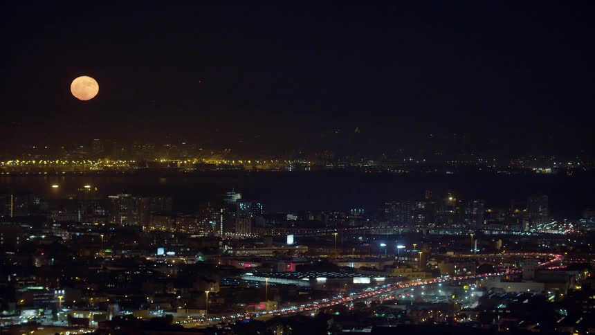 Large moon looms over a very large city