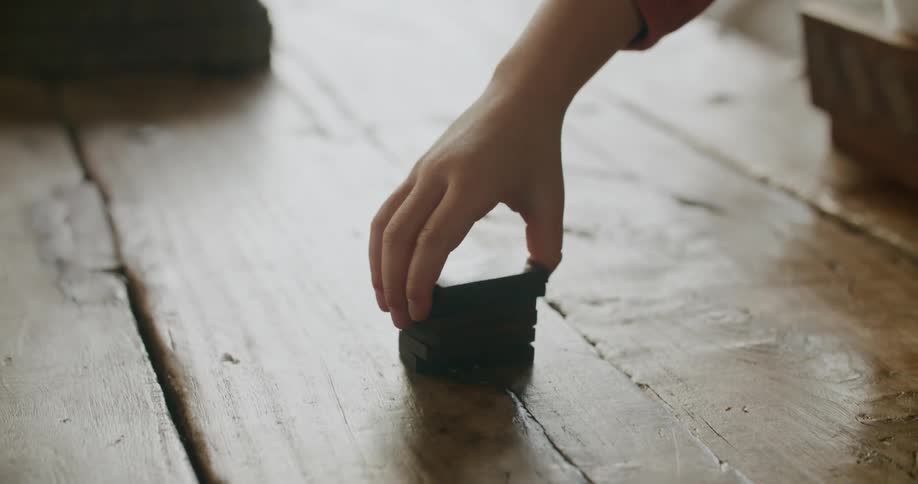 A person stacking dominos on the ground