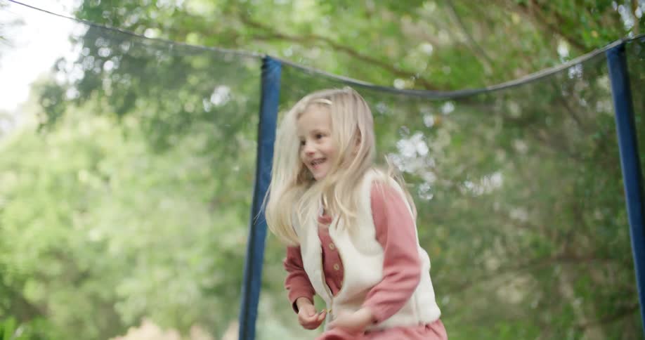 Blonde girl jumping on a trampoline in the backyard