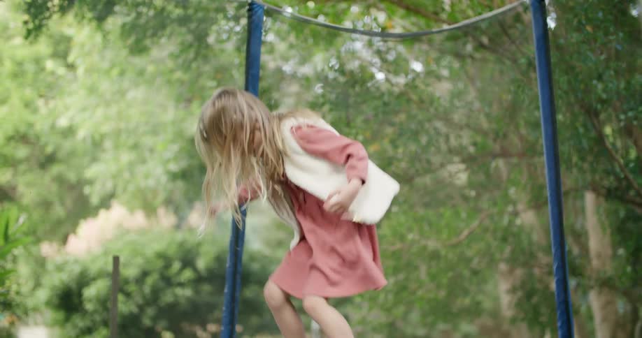 A girl laughs as she jumps on a trampoline in her backyard