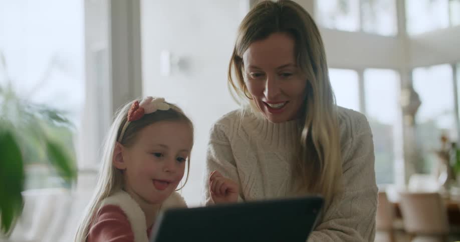 Mother and daughter at home playing on a tablet together