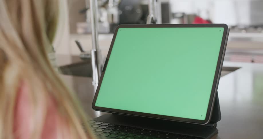 A laptop with a green replaceable screen sits on a kitchen counter