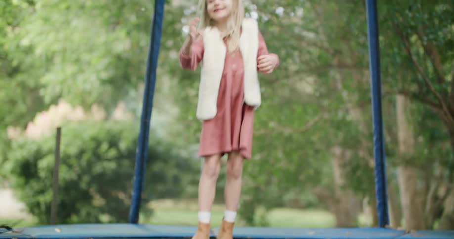 Blonde girl smiles while jumping on trampoline surrounded by protective net
