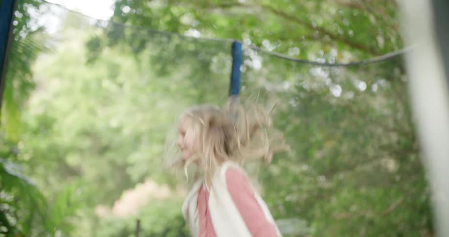 A young girl jumps on a trampoline outside