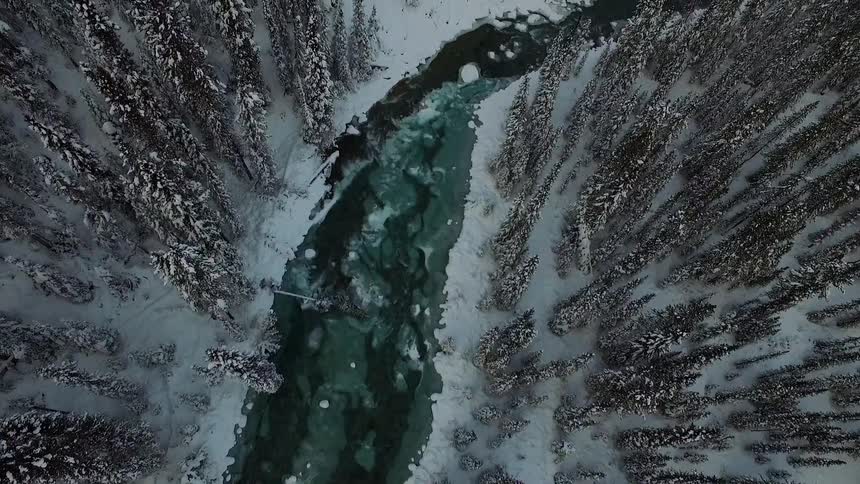 An aerial view of a snow covered forest and frozen river