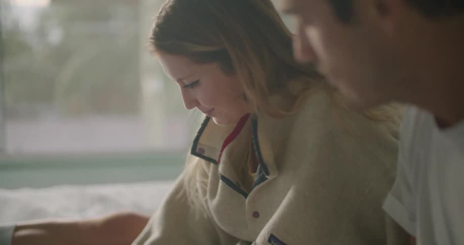 A father sits with his teenage daughter and helps her as she does homework