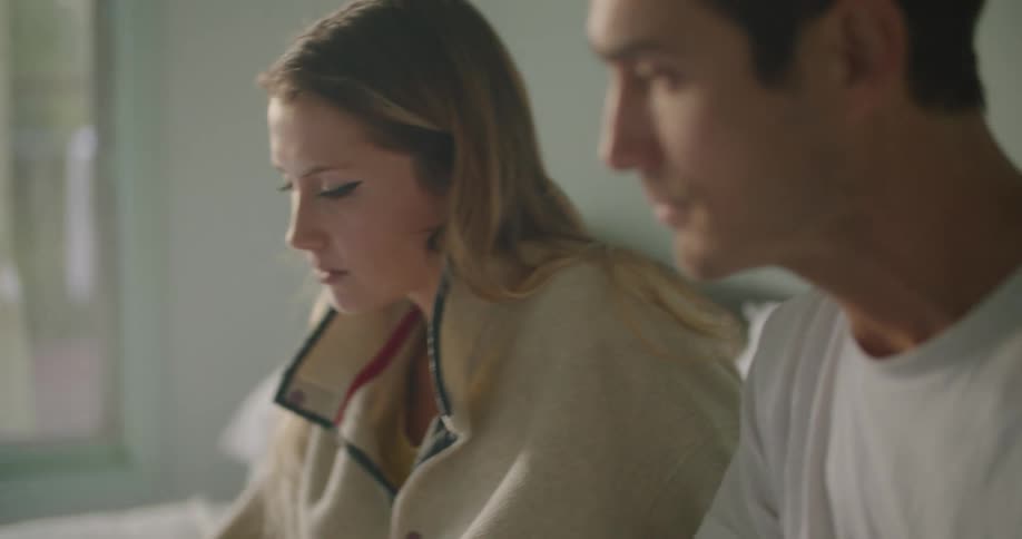 Young couple sitting in bed working on a laptop in the morning