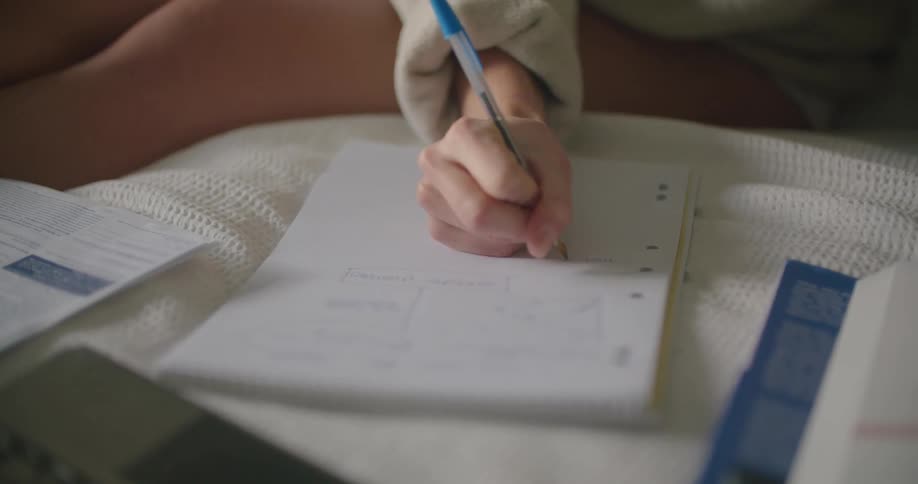 A person writing in a notebook with a pen