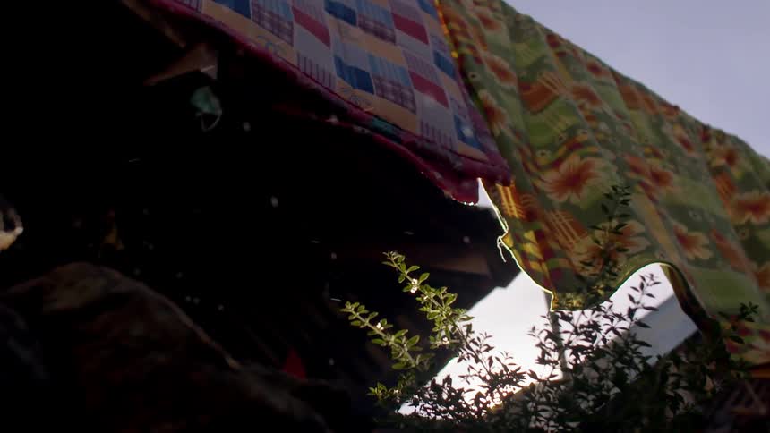 Water drops falling off of wet blankets hanging on clothesline
