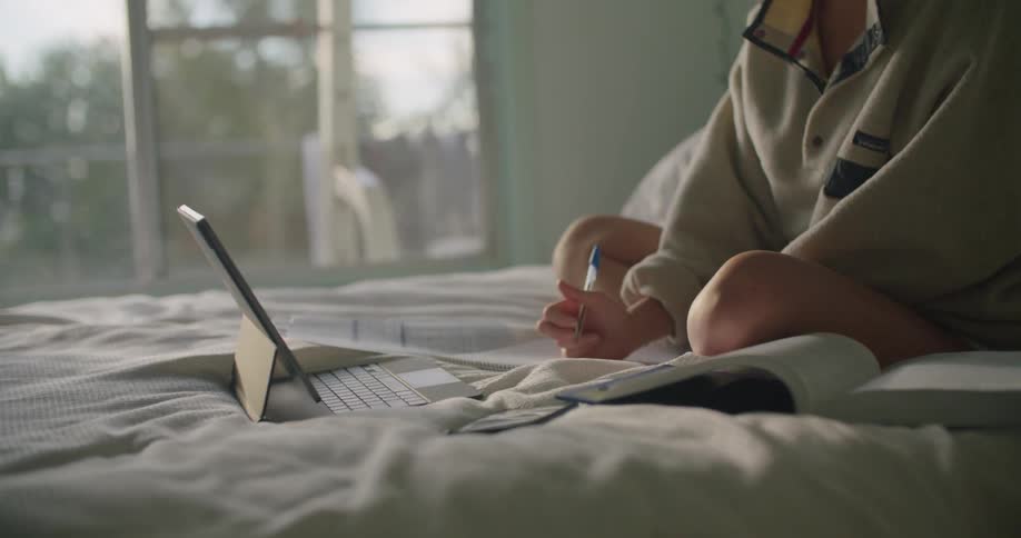 Woman sitting in bed working in front of a laptop in the morning