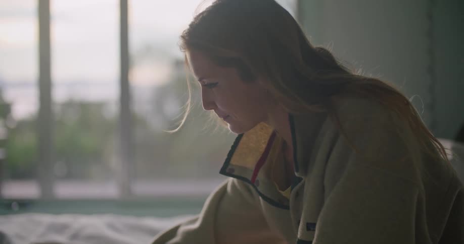 A woman sitting on a bed writing in a book