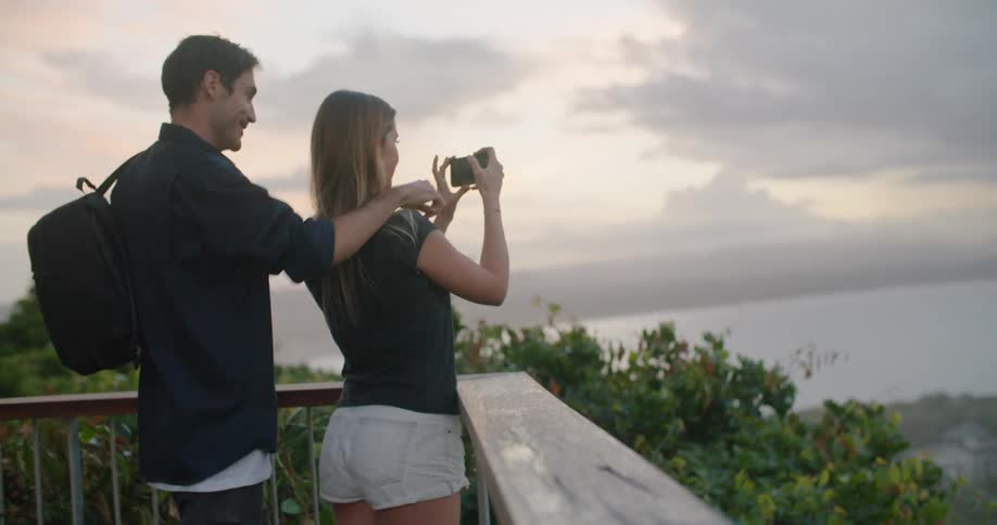 A man and woman taking photos of a sunset