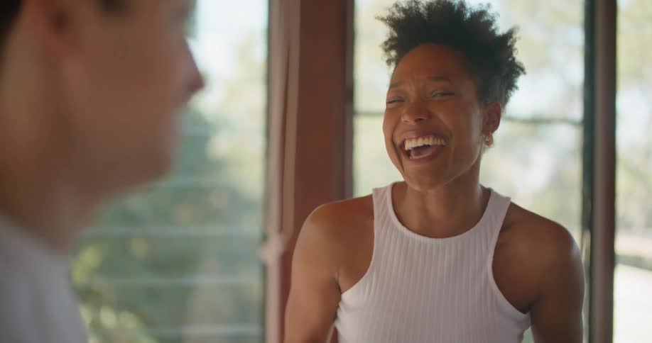A man and woman talk together standing in the room and the woman is laughing