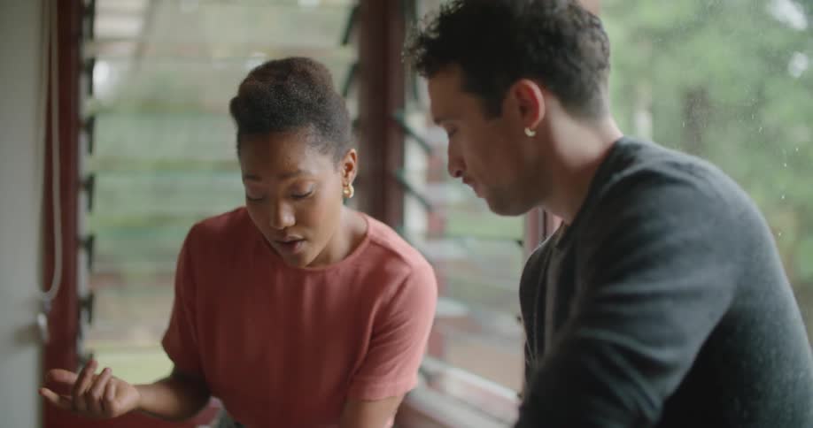 A couple look at a tablet together while sitting on a counter at home