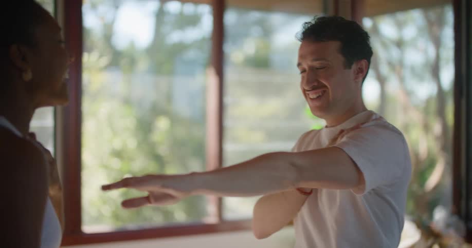 A woman laughs as she tries to demonstrate a move to a man