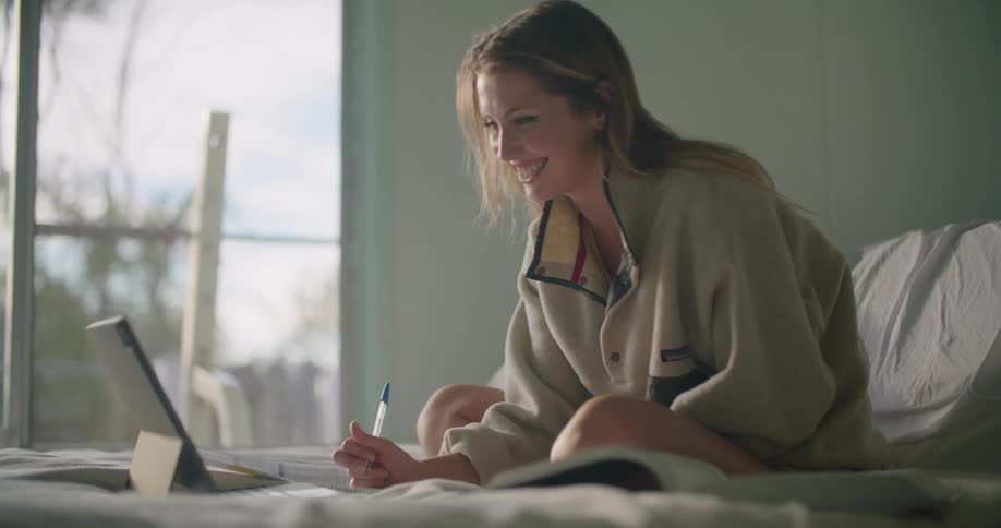 A woman using a laptop on her bed