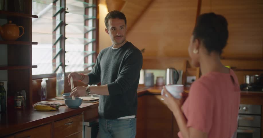 A man and a woman in a kitchen with a wall and window in the background