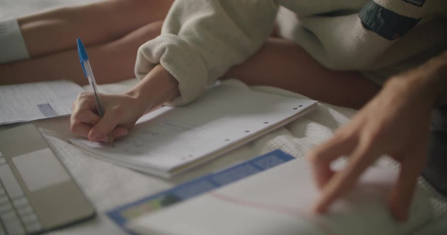 Young woman sitting in bed at home works taking notes on a notebook