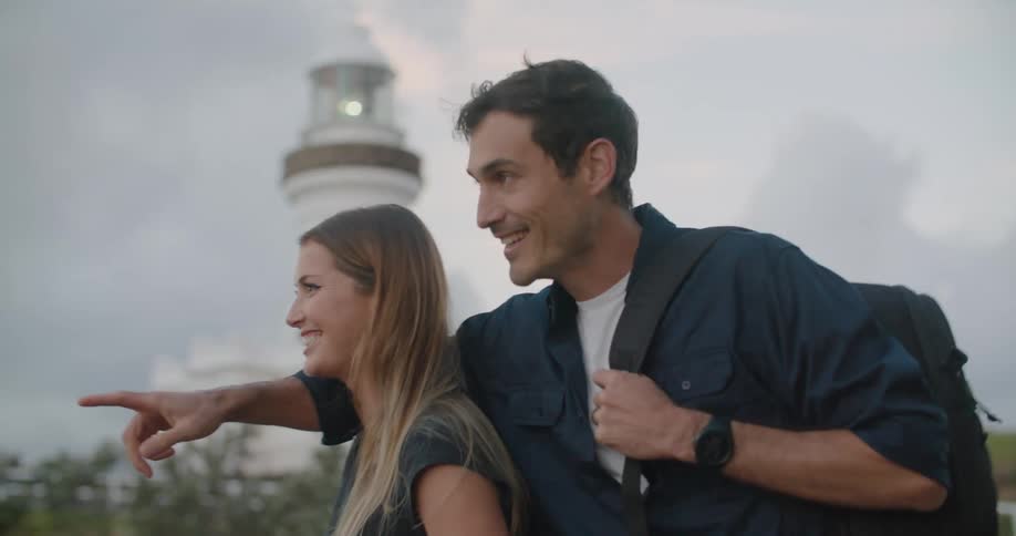 Man wearing dark blue shirt and backpack with blonde woman wander around lighthouse