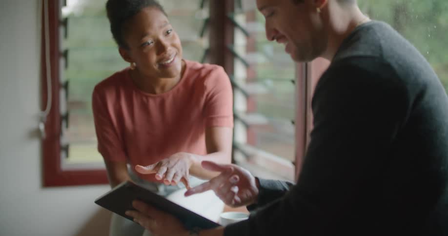 A woman talks to a man that is holding a tablet