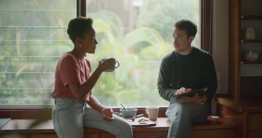 Young couple sitting on the kitchen countertop eating breakfast at home in the morning