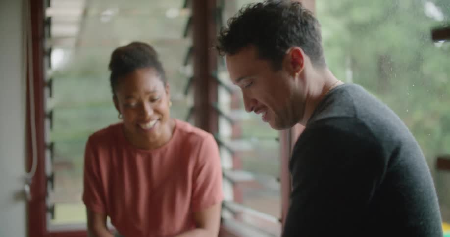 A woman gestures with her hands while talking to a man who is using a tablet