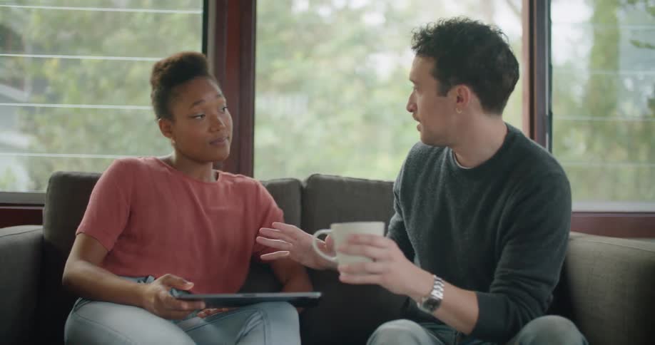 A man and woman talking with each other on the couch