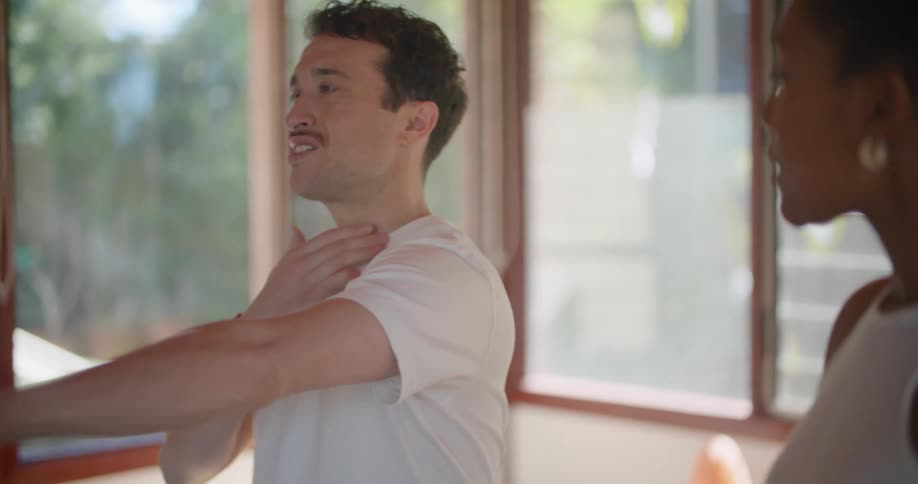 Woman teaching a man how to perform yoga poses at home