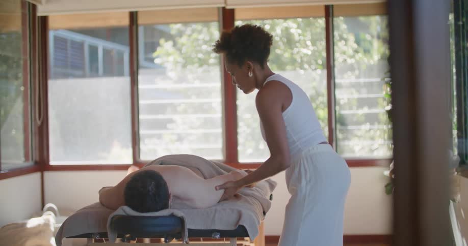 Massage therapist carefully moves mans arm as he lies on massage table